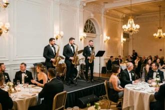 Quatuor de jazz en tuxedo jouant en direct lors d'un dîner de mariage dans une salle de réception élégante avec lustres dorés